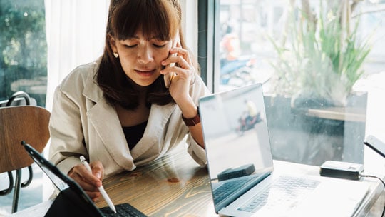 Woman talking on the phone while using a tablet